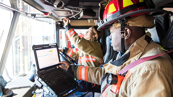 A stock photo of a female firefighter in the drivers seat of the fire engine.